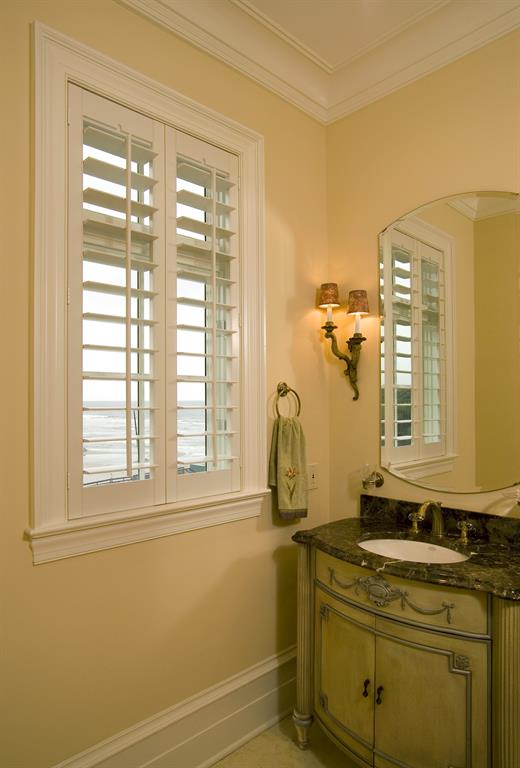 Plantation shutters in a light bathroom looking out over ocean